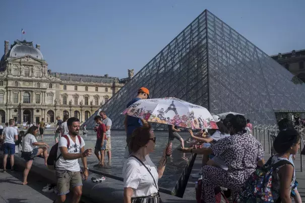 People cool off next to the fountains at Louvre Museum in Paris, France, Wednesday, July 24, 2019. Temperatures in Paris are forecast to reach 41 degrees C (86 F), on Thursday. Credit: Rafael Yaghobzadeh, AP