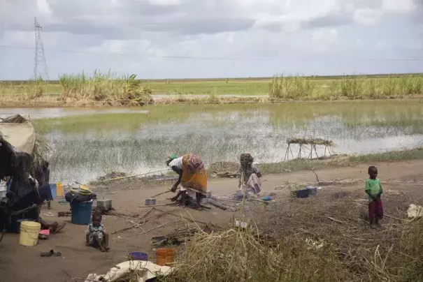 A mother prepares a meal for her family in a displacement camp on the bank of a flooded rice paddy near the village of Nicoadala, Zambezia province, Mozambique, Friday, March 24, 2023. Weeks after a massive cyclone hit Mozambique for a second time, the still-flooded country is facing a spiraling cholera outbreak which threatens to add to the devastation. (Credit: AP Photo/Tom Gould)