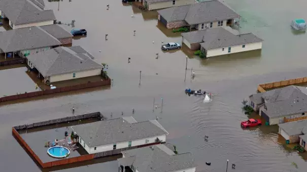 FILE- A boat motors between flooded homes after heavy rains inundating the region, in Hammond, La., on Aug. 13, 2016. (Credit: AP Photo/Max Becherer, File)