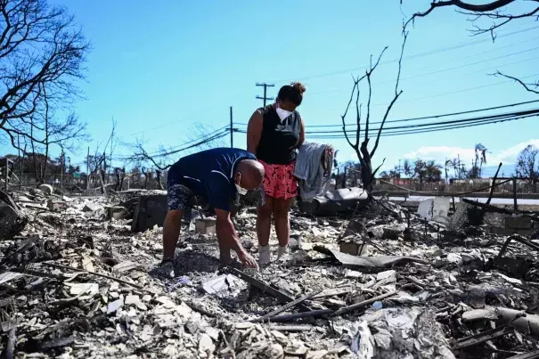 Davilynn Severson and Hano Ganer look for belongings through the ashes of their family's home on Friday in the aftermath of a wildfire in Lahaina, in western Maui, Hawaii. (Credit: Patrick T. Fallon/AFP via Getty Images)