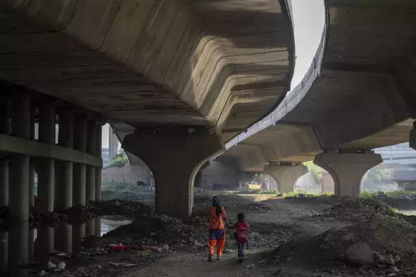 Meera Devi, left, accompanies her daughter Arima, 7, to her school as they walk on the flood plain of Yamuna River, in New Delhi, India, Friday, Sept. 29, 2023. (Credit: AP Photo/Altaf Qadri)