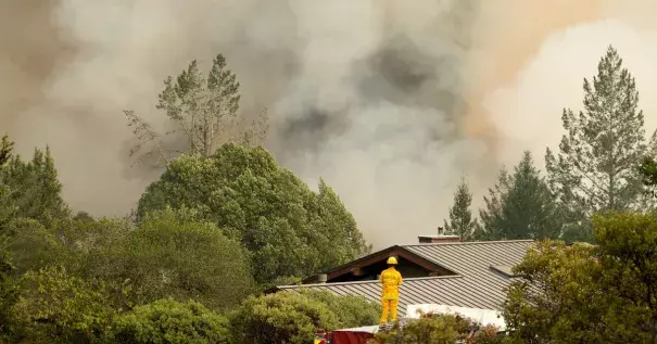 A firefighter watches smoke billow as flames approach a residential area in Sonoma in California in October. Photo: Josh Edelson, AFP/Getty Images