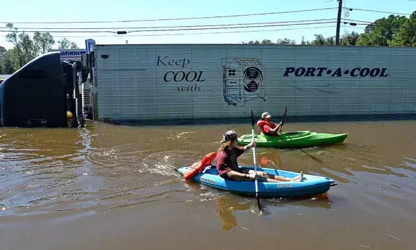 Anthony Writebol, left, and his cousin, Melissa Hill paddle past a stranded tractor trailer on Hwy 211 in Lumberton, N.C., Sunday, Oct. 9, 2016. Photo: Chuck Liddy, The Charlotte Observer via AP