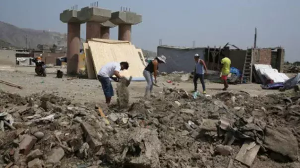 People clean a street a month after torrential rains, causing flooding and widespread destruction in Carapongo, Lima, Peru, April 18, 2017. Photo: Reuters