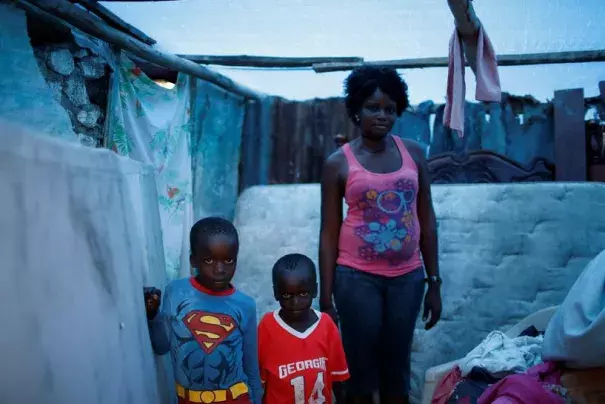 Marie Ange St Juste (R), 29, poses for a photograph with her sons, Kensley, 7 (L), and Peterley, 5, in their destroyed house after Hurricane Matthew hit Jeremie, Haiti, October 17, 2016. 'My house was totally destroyed during the storm,' said St Juste. 'I lost everything, but I was lucky that none of my children died. Now my situation is very bad, we need help.' Photo: Carlos Garcia